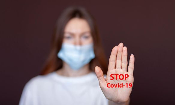 Coronavirus concept. Girl wearing mask for protection from disease and show stop hands gesture for stop corona virus outbreak. Global call to stay home. Stop the pandemic with vaccination