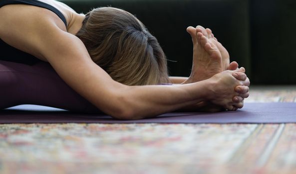 Woman Practices Yoga Asanas in Morning for Energy for the Whole Day. Yoga Lady Doing Seated Forward Bend Exercise Face Down.Close-up.