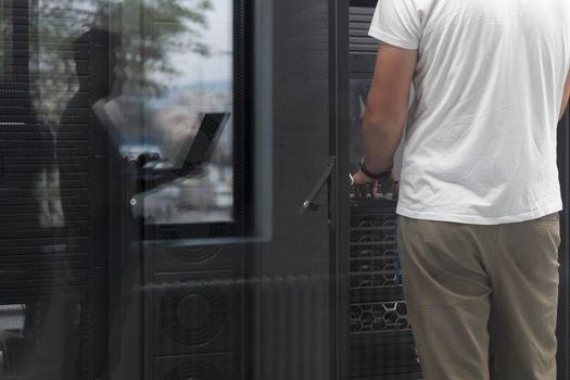 A couple of server engineers cooperate in high tech data centers. Technicians team updating hardware inspecting system performance in super computer server room or cryptocurrency mining farm.