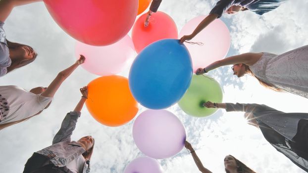 Cheerful girlfriends connect large colorful balls in a circle