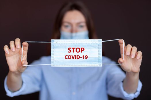 Coronavirus concept. Girl wearing mask for protection from disease and show stop hands gesture for stop corona virus outbreak. Global call to stay home. Stop the pandemic with vaccination.Mask in hand