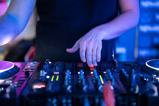 Close up Front view of of DJ hands controlling a music table in a night club. High quality photo