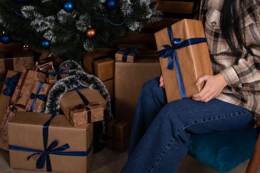 female hands holding brown gift box with a blue bow on it. new year, christmas, winter, presents.