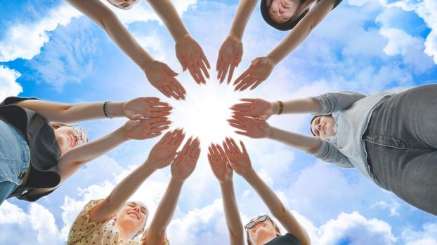 Joyful girls pull their palms to the center against the backdrop of a fabulous sky