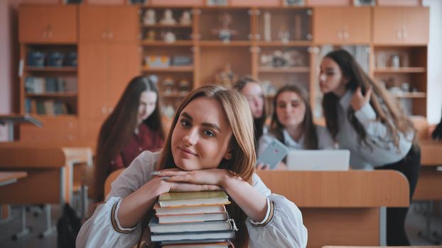 A student poses with textbooks at her desk in her class