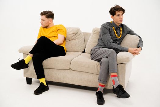Two Friends Quarreled and Sat on Opposite Sides of the Sofa. Men are in a Quarrel and sit on the Couch at a Distance from Each Other. Close-up. High quality photo