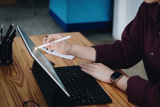 A female employee is pointing a pen at a tablet to buy shares on a trading board via the internet