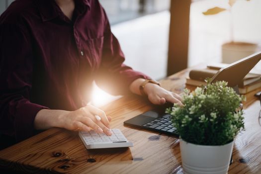 A female company employee is using a calculator to calculate sales income on a tablet computer screen via the Internet