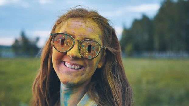 Cheerful girl posing smeared in multi-colored powder