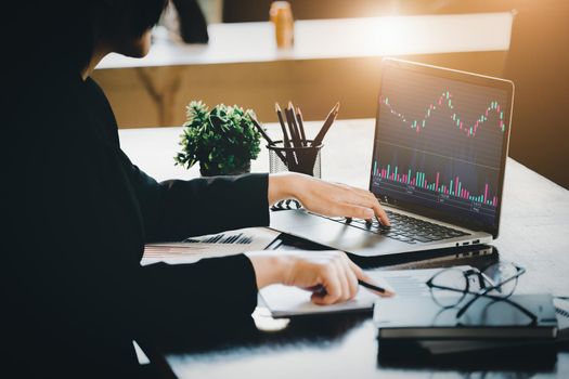 Financial and investment planning concept, female businesswoman using computer to analyze charts to find entry points on a trading board. through digital media via the internet