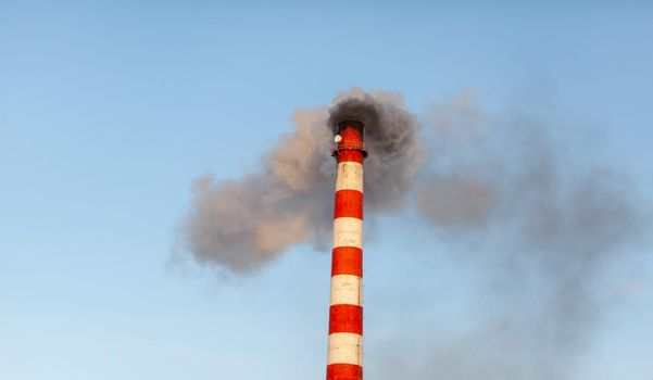 White thick smoke from the boiler room chimney. Smoke against the blue sky. Air pollution. Heating of the city. Industrial zone.