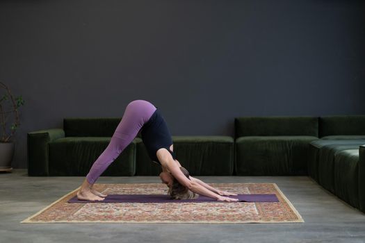 Dog Pose, Yoga. Lovely woman doing a stretch at a morning class in an apartment in megapolis. Concept of caring for body in an urban setting. High quality photo