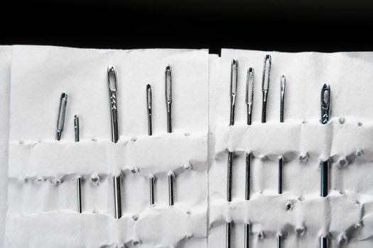 A set of sewing needles. Sewing and needlework classes.Workshop of hand craft and handmade.Workplace of the textile industry. Embroidery needles in a white package. Needle Factory