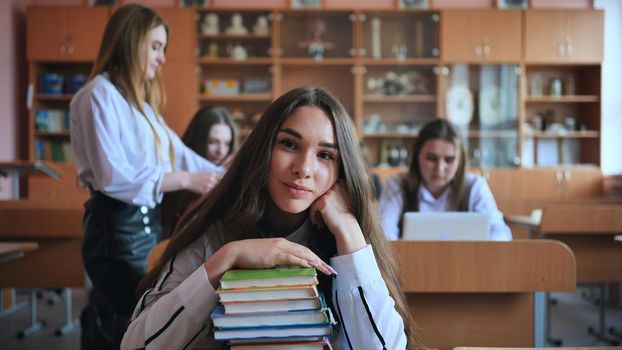 A student poses with textbooks at her desk in her class