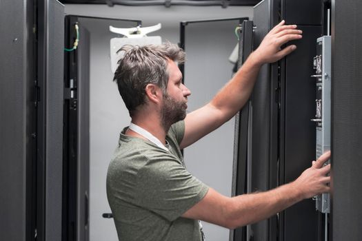 IT engineer working In the server room or data center. The technician puts in a rack a new server of corporate business mainframe supercomputer or cryptocurrency mining farm.