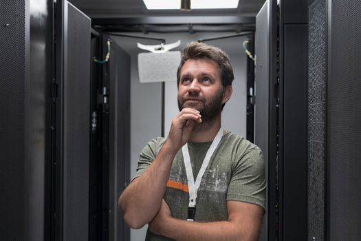 Portrait of male technician or network administrator standing brave as a hero with arms crossed in data center server room. High quality photo