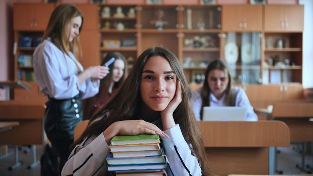 A student poses with textbooks at her desk in her class