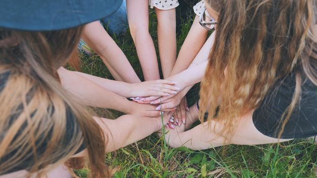Girls friends join hands on the grass in the park