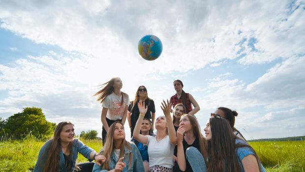 Female student girls standing in a circle toss the world globe up