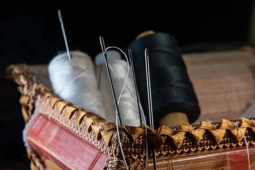 The thread is threaded through the eye of a sewing needle.Sewing and needlework classes.Workshop of hand craft and handmade.Workplace of the textile industry.The embroidery needle is stuck in a bobbin