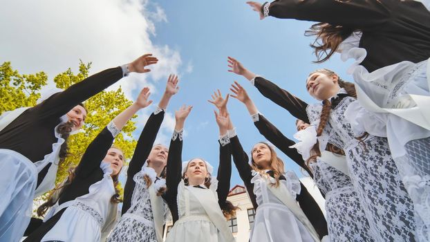 Happy Russian graduates join their hands on the last day of the school day