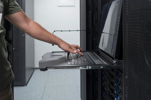 Close up on Data Center Engineer hands Using keyboard on a supercomputer. Server Room Specialist Facility with Male System Administrator Working with Data Protection Network for Cyber Security.