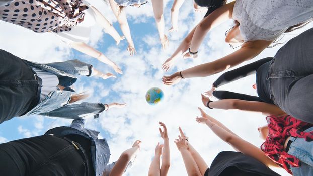 Female student girls standing in a circle toss the world globe up