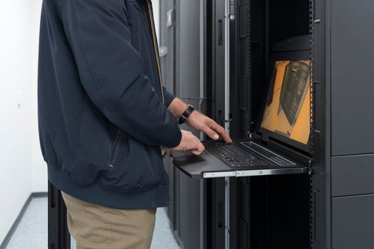 Close up on Data Center Engineer hands Using keyboard on a supercomputer. Server Room Specialist Facility with Male System Administrator Working with Data Protection Network for Cyber Security.