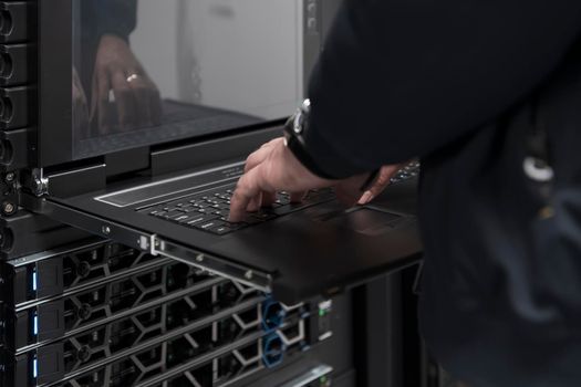 Close up on Data Center Engineer hands Using keyboard on a supercomputer. Server Room Specialist Facility with Male System Administrator Working with Data Protection Network for Cyber Security.