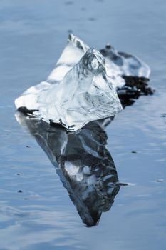 Isolated piece of iceberg melting with reflection over the beach