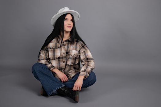 portrait of beautiful young woman in brown checkered shirt and jeans on gray background. pretty female portrait.