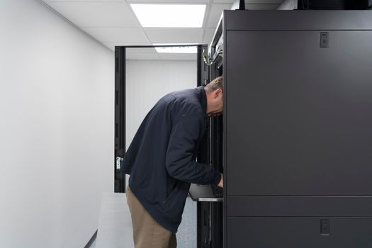 A couple of server engineers cooperate in high tech data centers. Technicians team updating hardware inspecting system performance in super computer server room or cryptocurrency mining farm.