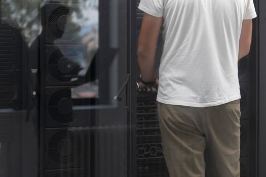 Close up on Data Center Engineer hands Using keyboard on a supercomputer. Server Room Specialist Facility with Male System Administrator Working with Data Protection Network for Cyber Security.