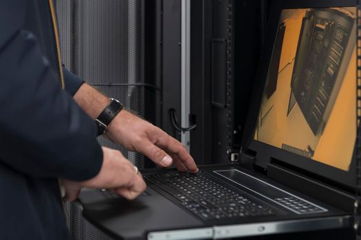 Close up on Data Center Engineer hands Using keyboard on a supercomputer. Server Room Specialist Facility with Male System Administrator Working with Data Protection Network for Cyber Security.