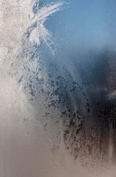 Winter snow patterns on frosted glass. window covered with frost close up