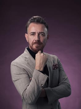 Portrait of a stylish elegant senior businessman with a beard and casual business clothes in photo studio isolated on dark background gesturing with hands. High quality photo