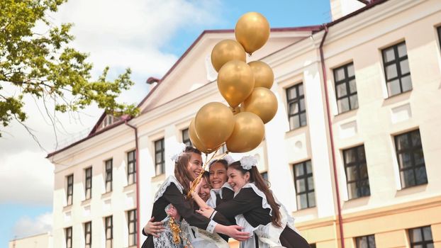 Cheerful Russian girls graduating with orange balloons on the last school day