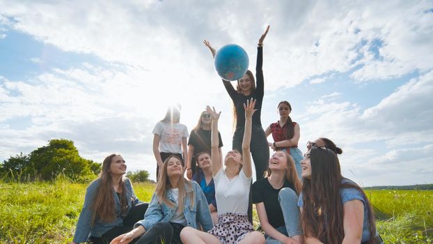 Female student girls standing in a circle toss the world globe up
