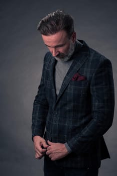 Portrait of a stylish elegant senior businessman with a beard and casual business clothes in photo studio isolated on dark background gesturing with hands. High quality photo