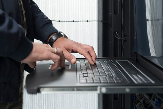 Close up on Data Center Engineer hands Using keyboard on a supercomputer. Server Room Specialist Facility with Male System Administrator Working with Data Protection Network for Cyber Security.