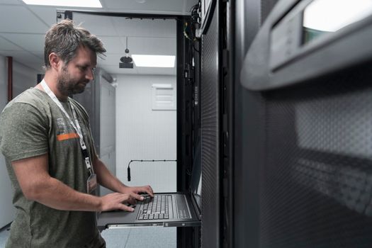 Data Center Engineer Usaing Keyboard on a Supercomputer. Server Room Specialist Facility with Male System Administrator Working with Data Protection Network for Cyber Security or Cryptocurrency Mining Farm