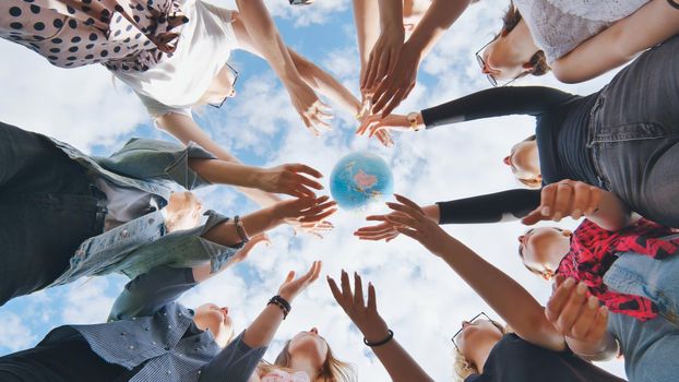 Female student girls standing in a circle toss the world globe up