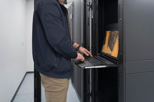 Close up on Data Center Engineer hands Using keyboard on a supercomputer. Server Room Specialist Facility with Male System Administrator Working with Data Protection Network for Cyber Security.