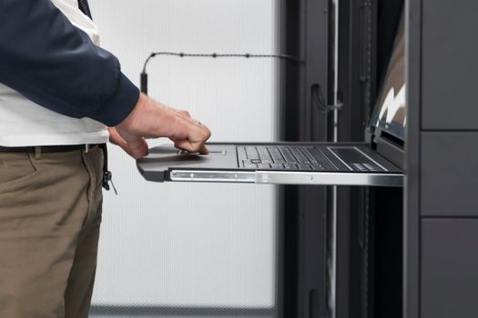 Close up on Data Center Engineer hands Using keyboard on a supercomputer. Server Room Specialist Facility with Male System Administrator Working with Data Protection Network for Cyber Security.