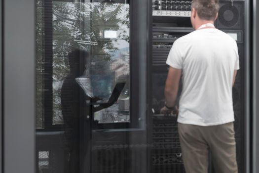 A couple of server engineers cooperate in high tech data centers. Technicians team updating hardware inspecting system performance in super computer server room or cryptocurrency mining farm.