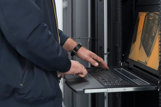 Close up on Data Center Engineer hands Using keyboard on a supercomputer. Server Room Specialist Facility with Male System Administrator Working with Data Protection Network for Cyber Security.