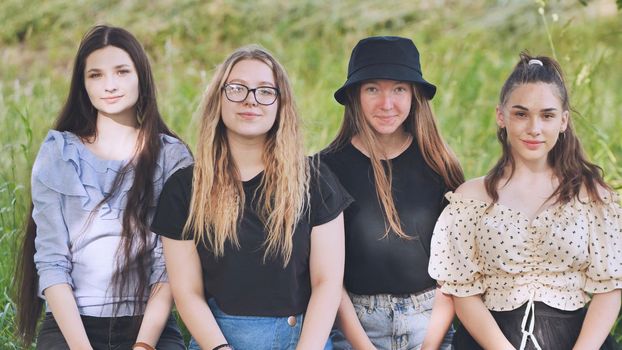 Girls cover their faces with a toy Pop It while sitting in the park