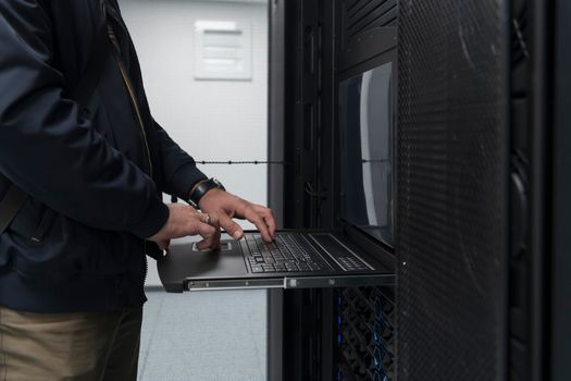 Close up on Data Center Engineer hands Using keyboard on a supercomputer. Server Room Specialist Facility with Male System Administrator Working with Data Protection Network for Cyber Security.