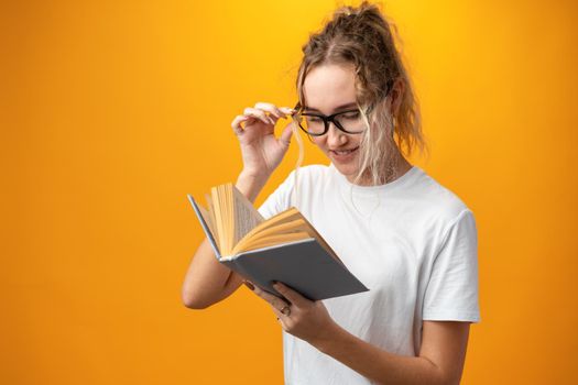 Cute pretty girl with books on yellow background, close up