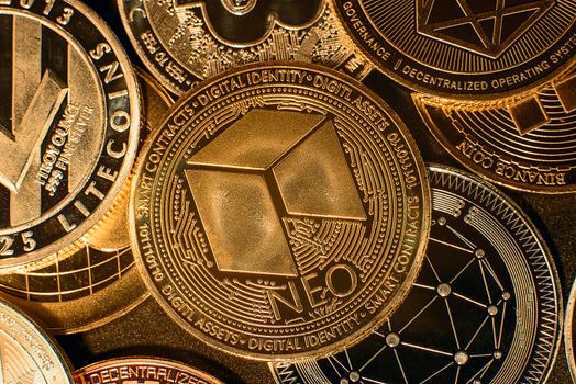Horizontal view of cryptocurrency tokens, including NEO, Bitcoin, dogecoin, and Ethereum saw from above on a black background. High quality photo